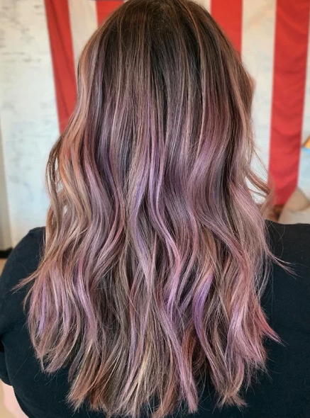 Medium length dirty blonde wavy hair with purple highlights. 