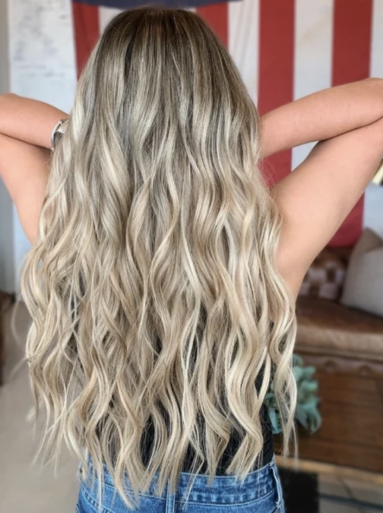 Long bright blonde hair with hip length extensions.