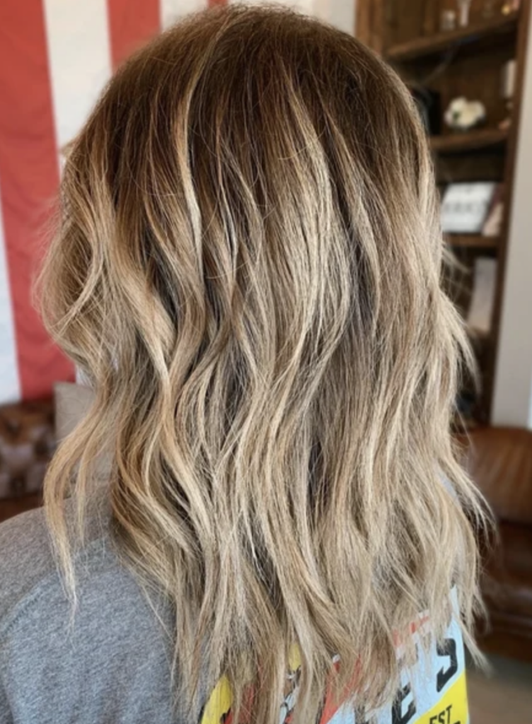 Medium length dirty blonde hair with highlights and a shadow root.