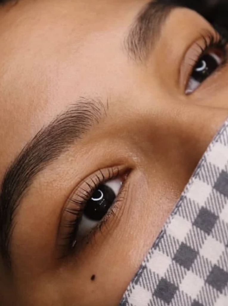 A woman's brown eyes and she has natural looking eyelash extensions and groomed eyebrows. 