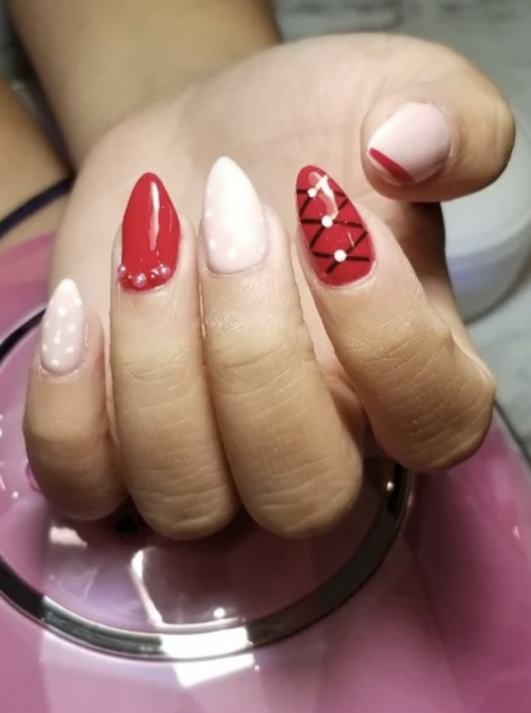 Long almond shaped red, white and nude nails with decals including black stripes, white dots and a red french tip. 