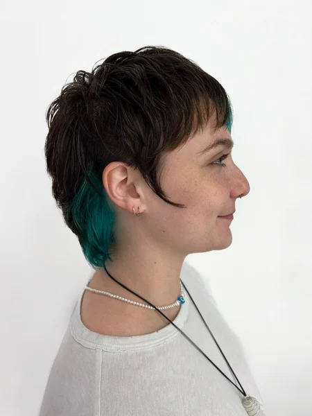 Photo of woman with brunette mixie haircut with pop of green color
