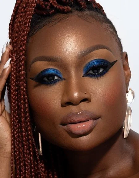 A woman with bright blue eyeshadow up to the crease and winged eyeliner that wraps under the eye. 