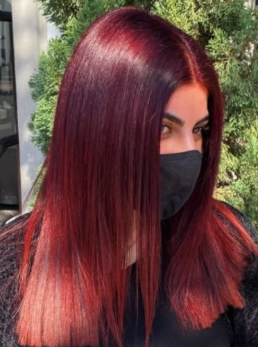 A woman with deep maroon colored straight hair. 