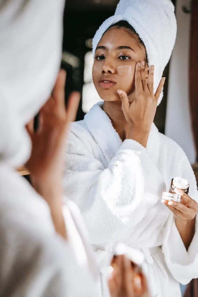 Woman looking in the mirror applying a face cream. 