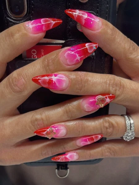 Airbrushed pink and red nails with white heart decals. 