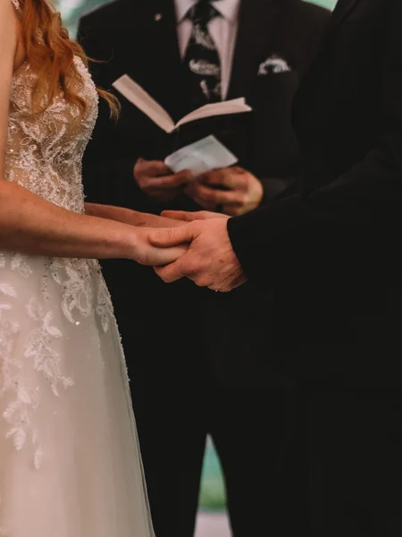 A close up shot of a bride and groom holing hands at the altar. 