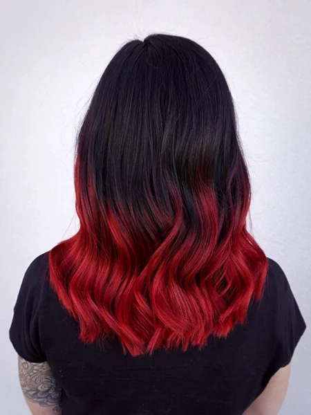 Back of a woman's head with ombre hair that goes from black to bright red. 