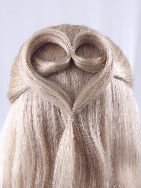 Blonde hair is twisted in the back to form the shape of a heart. 