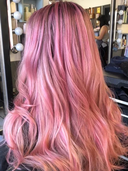 Woman with long, wavy hair dyed bubblegum pink. 