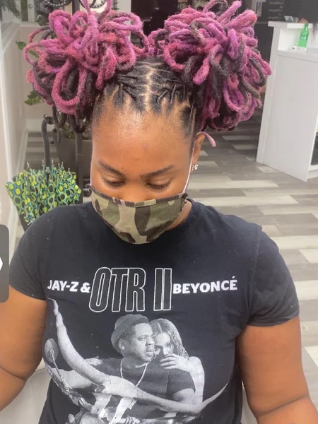 Black woman with black and pink braided hair styled into two space buns.