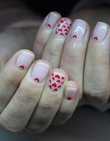 Nude manicure with a bunch of tiny, red hearts. 