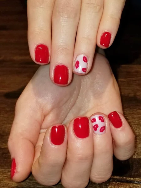 A red manicure with a ring finger accent nail that has lip/kiss decals. 