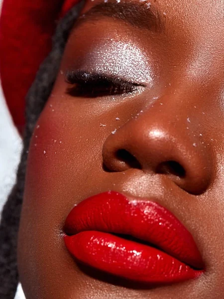 Black woman wearing silver eyeshadow and bright red lipstick. 