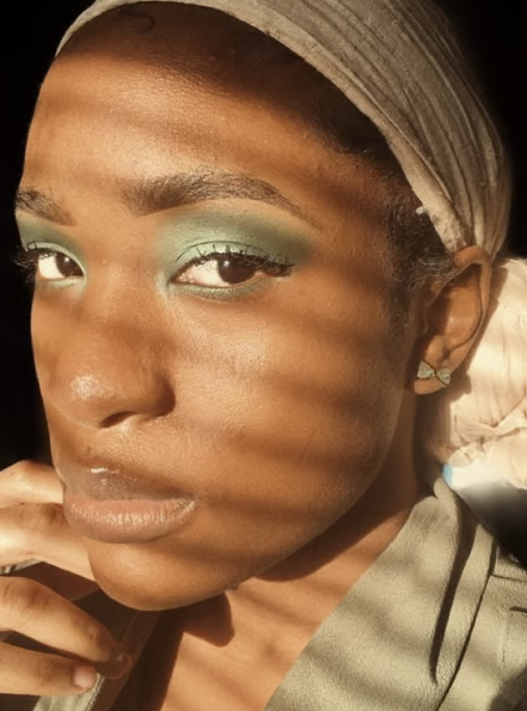 A woman with sage green eyeshadow blended to cover the entire eyelid and lower lash line. 