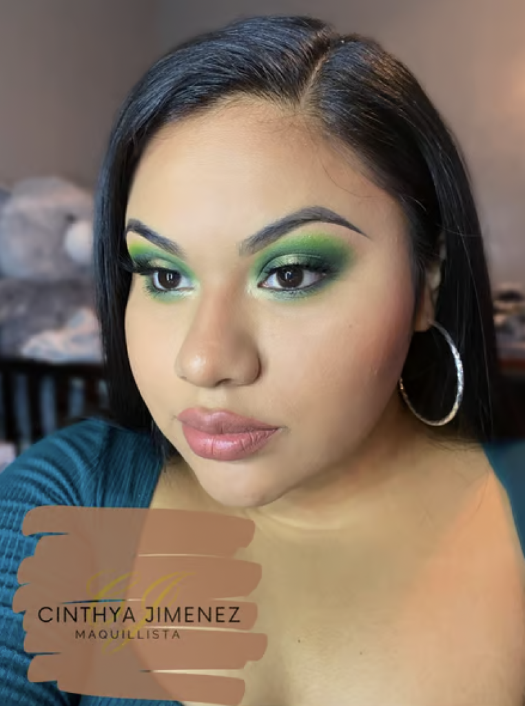 A woman wearing green eye makeup that consists of many different shades of green blended upwards. 