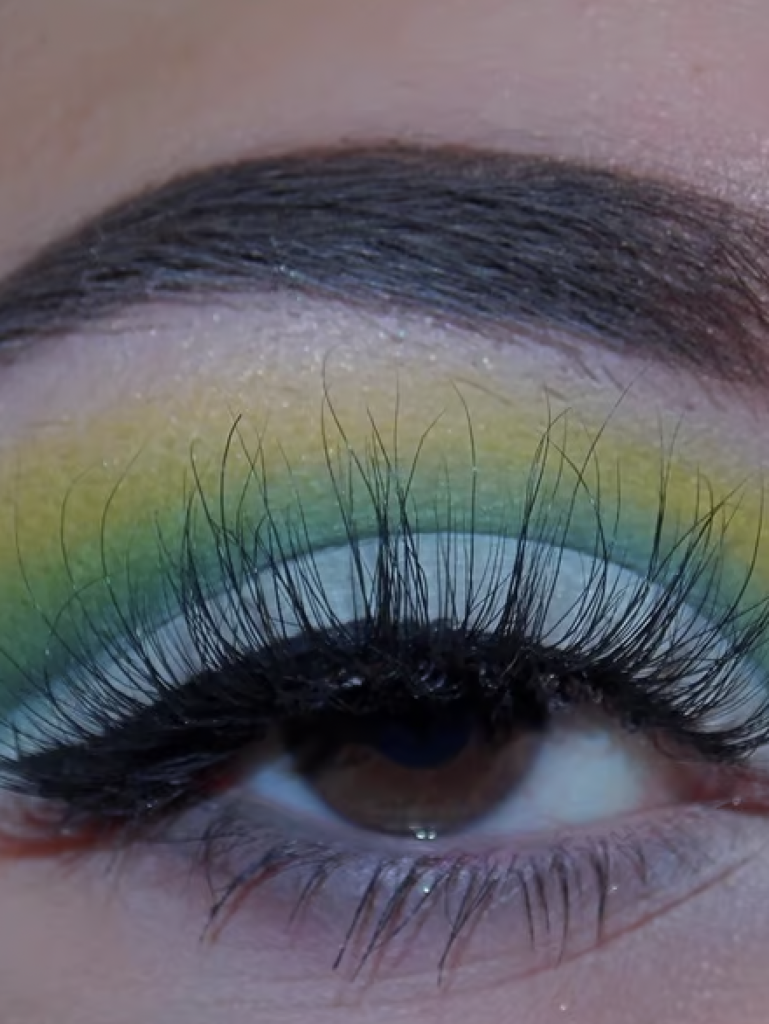 A close up image of an eye with eyeshadow that consists of different shades of green stacked on top of each other for the perfect St. Patrick's Day look. 