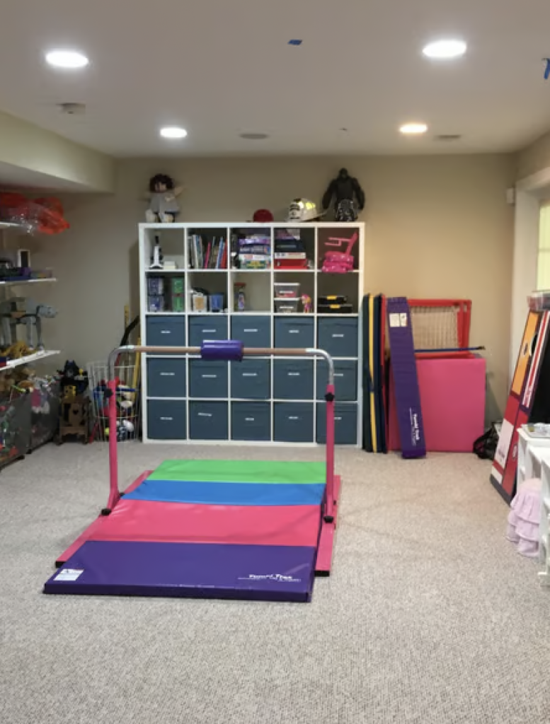 A kid's playroom with gymnastics equipment that has been organized. 