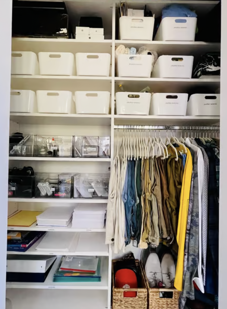 A closet with lots of shelves with bins and a small hanging section organized by color. 