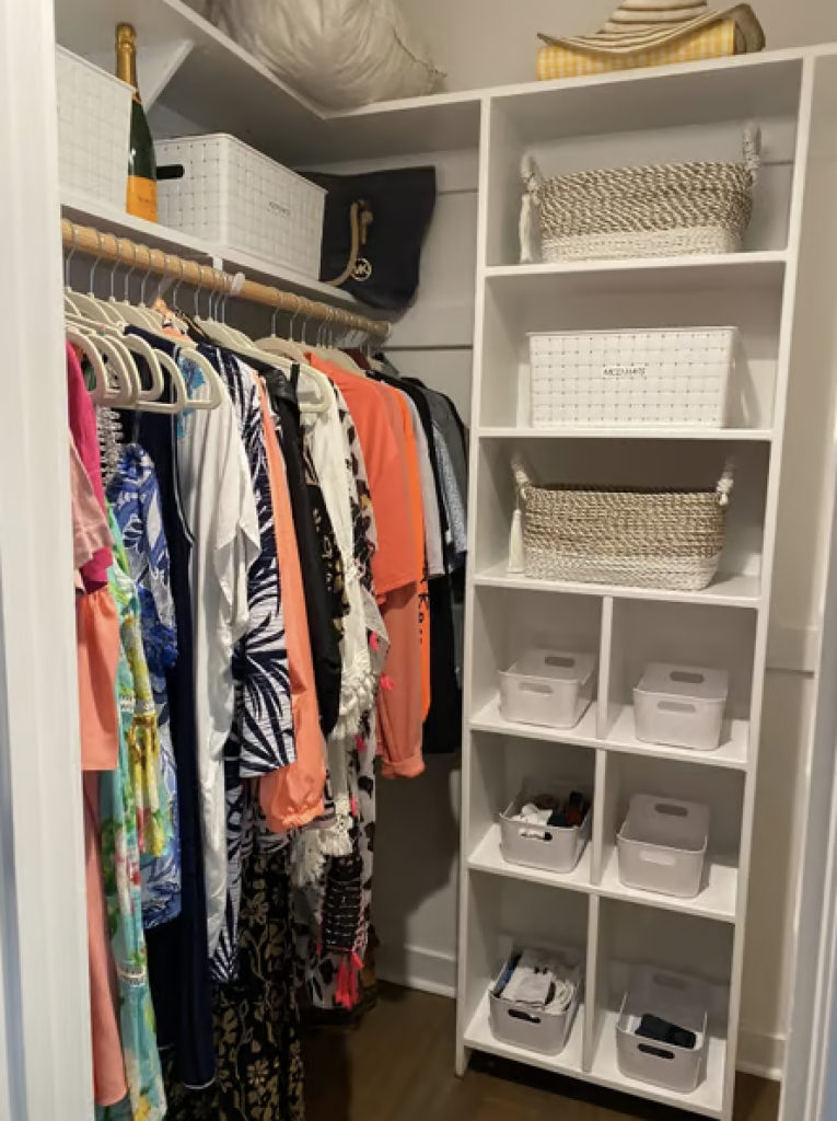 Small walk in closet that has been organized with lots of storage bins. 