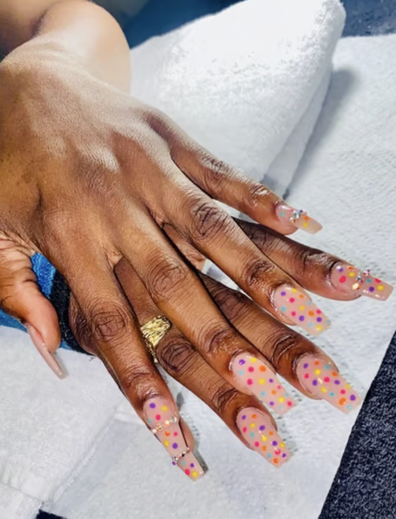 Long nails with a nude base and bright colored polka dots covering each nail. 