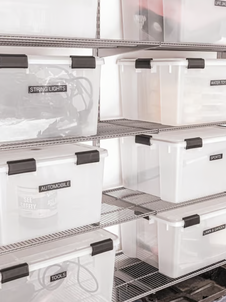 Clear plastic boxes stored on metal shelves being used to organize tools and outdoor items. 