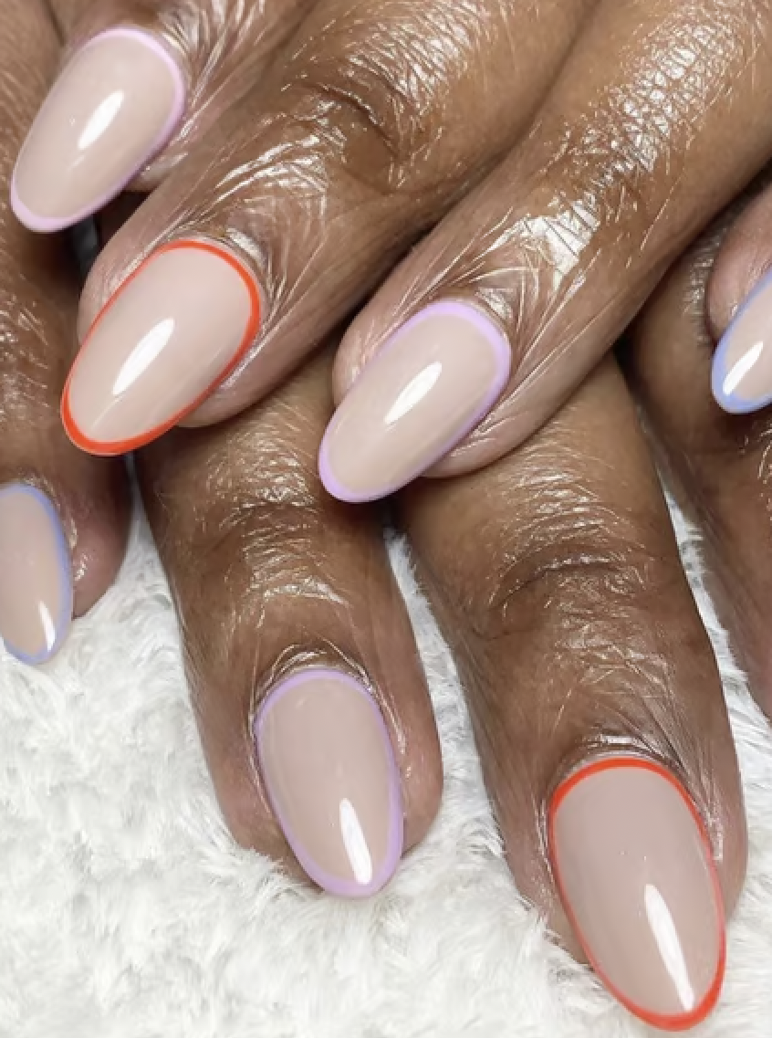 Medium length nails with a light base color and an orange and purple outline around each nail. 