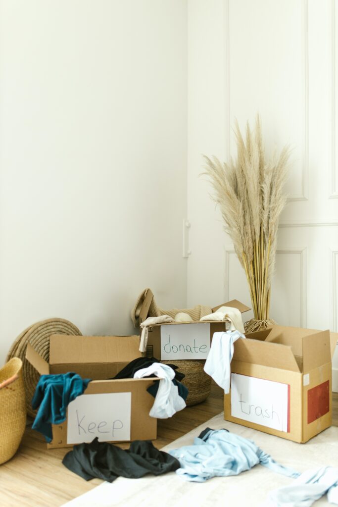 Stock image of 3 boxes filled with clothes and labeled keep, donate and trash