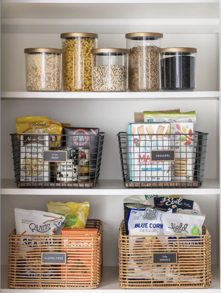 An aesthetic pantry with glass jars filled with grains and wire baskets filled with snacks. 
