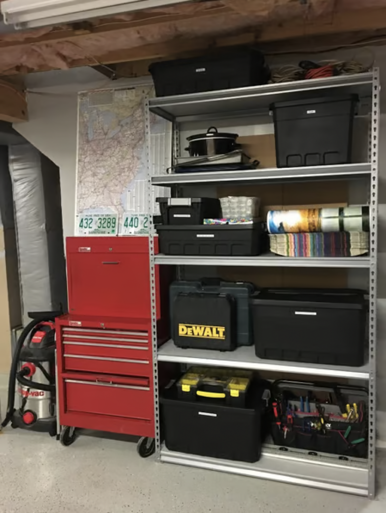 An organized garage storage shelf with large and labeled bins. 