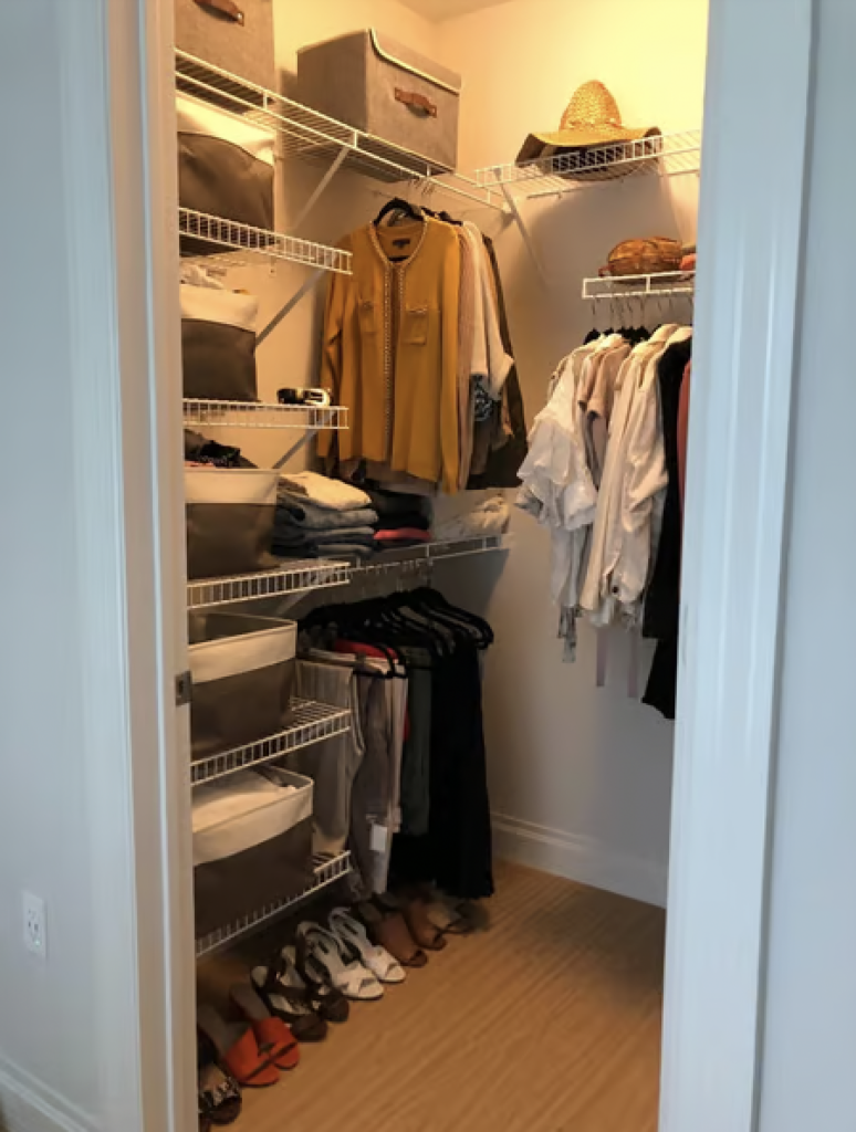 An after photo of a closet that has been organized with clothes now hanging on hangers and folded into cloth baskets. 