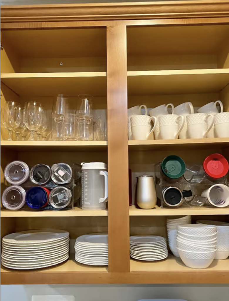 An organized kitchen cabinet with glasses, mugs, and plates. 