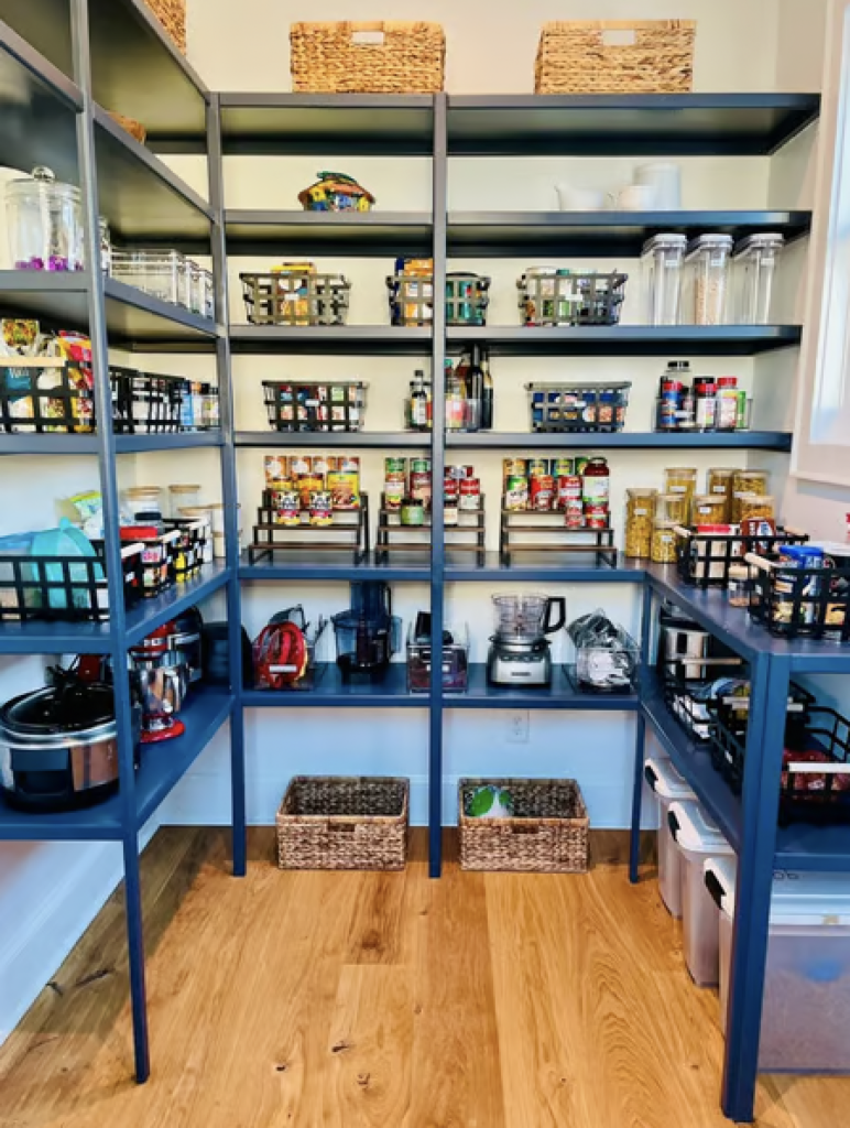 A professionally organized walk in pantry with black wire bins and clear storage containers 