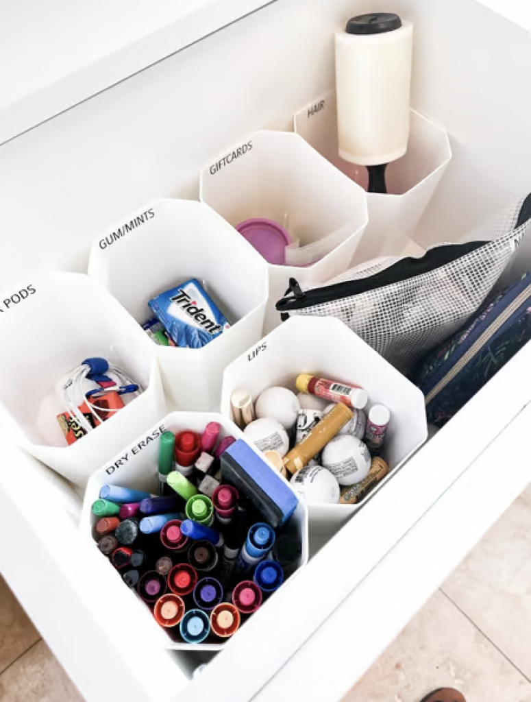 A "junk drawer" with octagon storage bins that hold and organize pens, chapsticks, gum, gift cards, and other items. 
