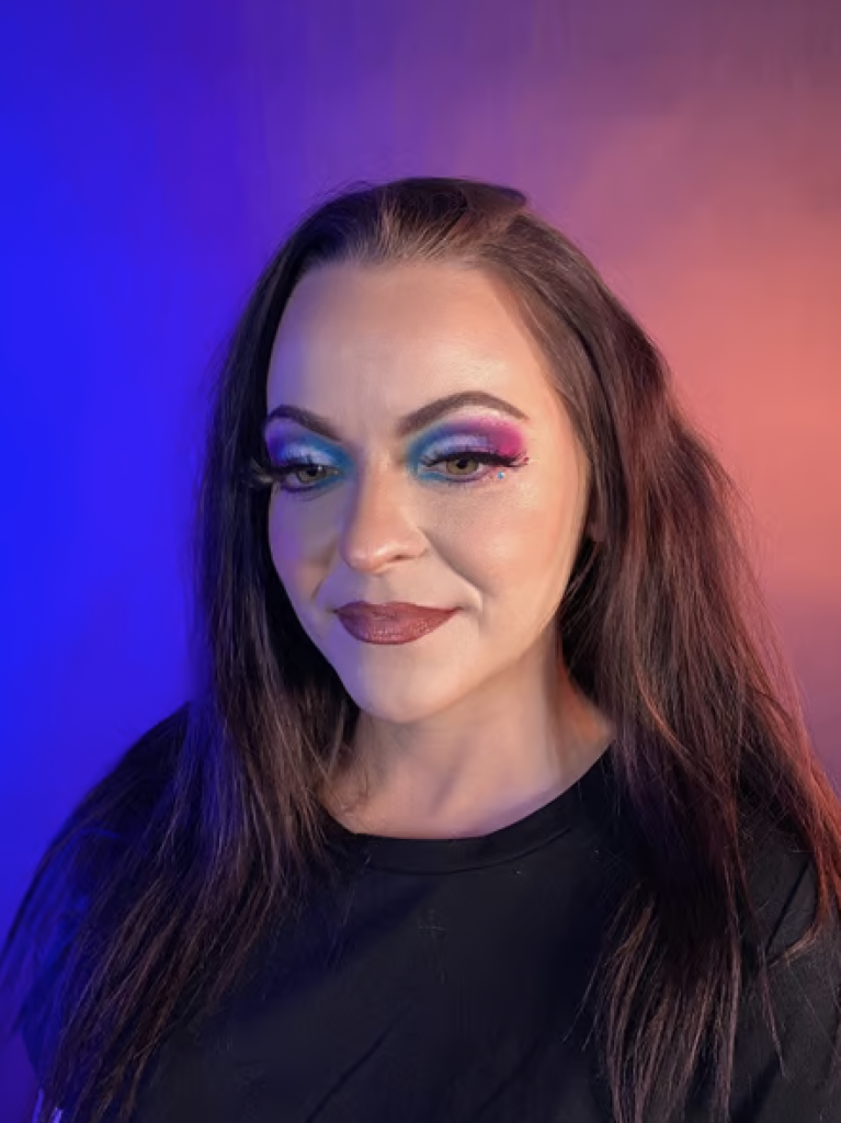A woman with blue eyeshadow on her inner corner, pink eyeshadow on the outer corner, and white eyeshadow on her eyelid. 