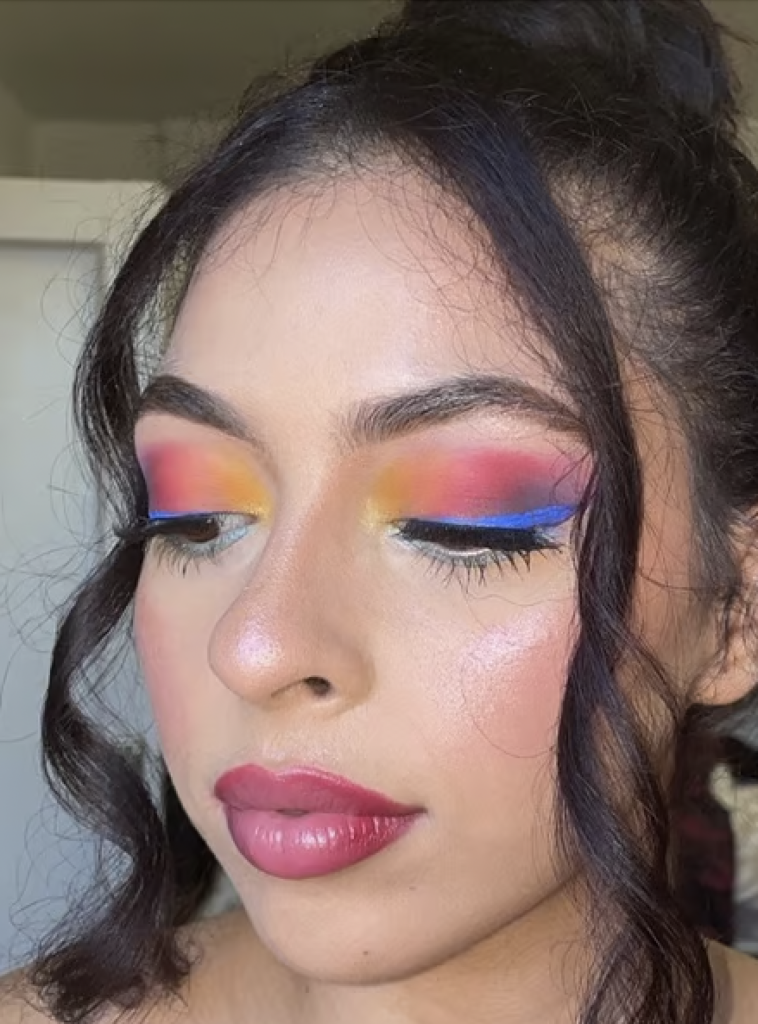 A blended eyeshadow look with yellow on the inner corner, pink on the crease and a bright blue eyeliner. 