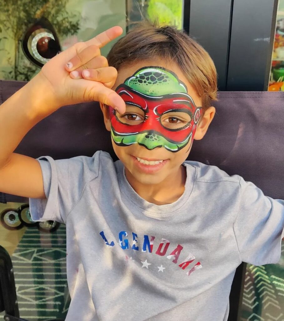 A child with green and red Teenage Mutant Ninja Turtles face paint 