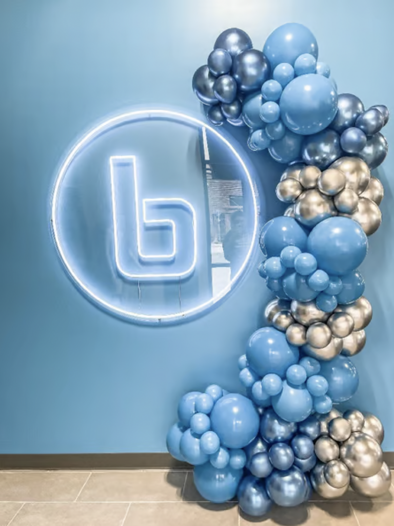 blue and silver balloon garland around a company's logo for a corporate event. 