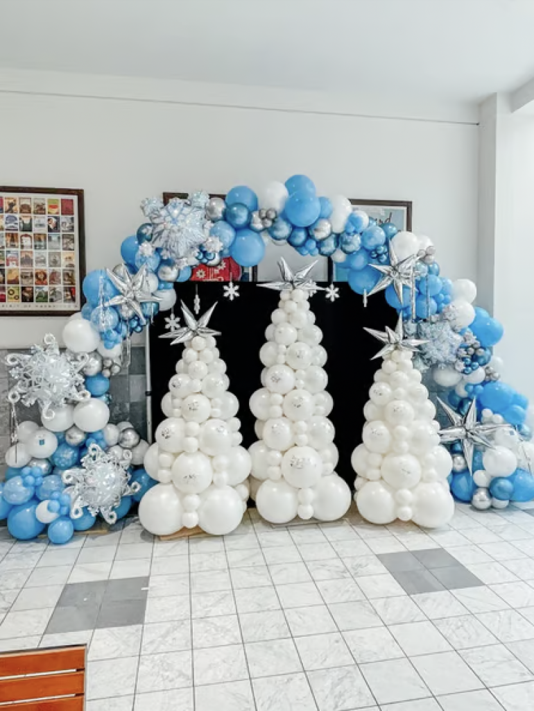 A large blue and silver balloon arch and white balloon "trees" decorated with silver spike balloons creating a winter wonderland. 