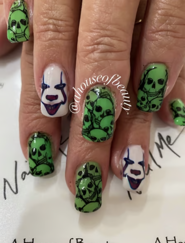 An "It" movie inspired manicure with red and white clown face and green and black skulls. 
