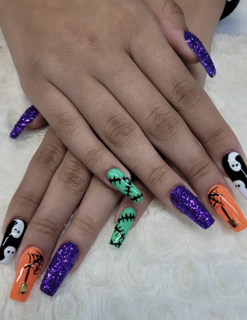 Multi-colored manicure with purple sparkles, black and white ghosts, orange spider webs, and green Frankenstein designs. 