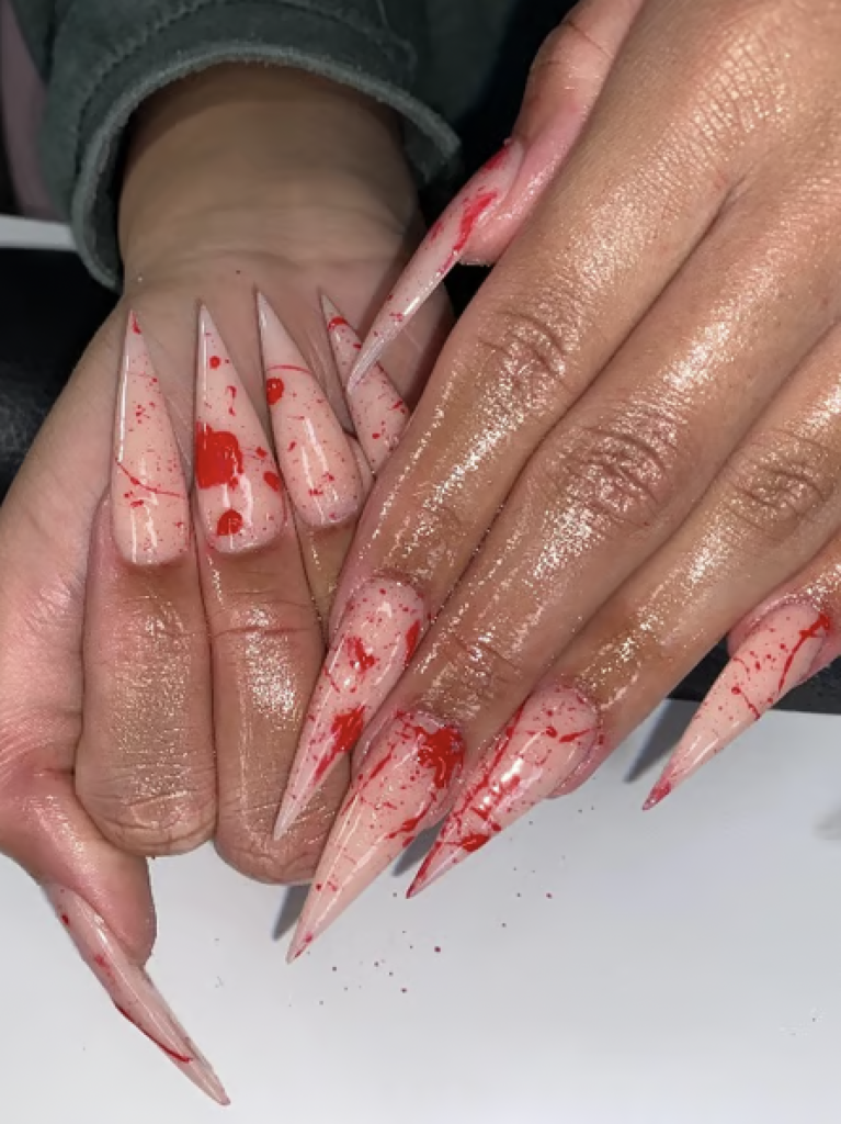 Long pointed manicure with blood splatter decals on each finger. 