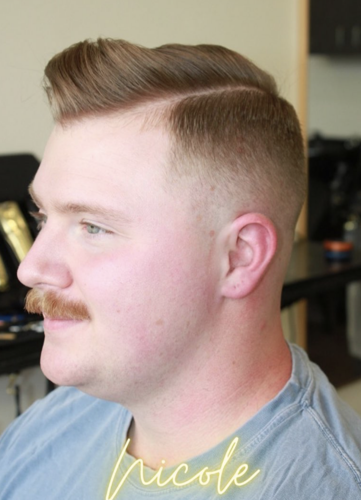 Man with a trimmed mustache and fresh haircut with shaved sides and long top. 